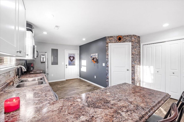 kitchen with sink, electric panel, dark hardwood / wood-style floors, white cabinets, and kitchen peninsula