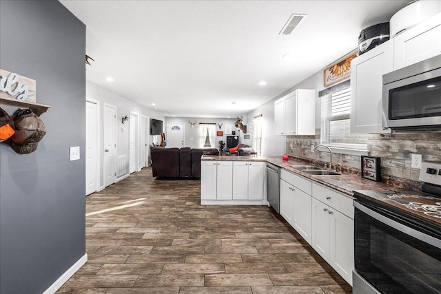 kitchen with white cabinetry, appliances with stainless steel finishes, kitchen peninsula, and sink