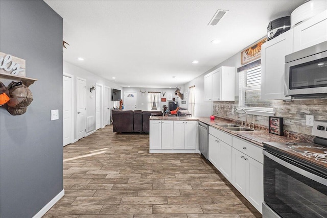 kitchen featuring white cabinetry, sink, stainless steel appliances, and kitchen peninsula