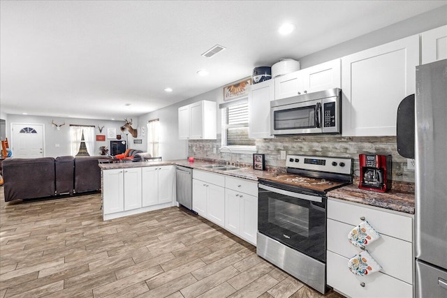 kitchen featuring sink, white cabinets, decorative backsplash, kitchen peninsula, and stainless steel appliances