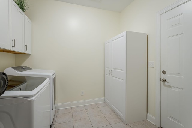 washroom featuring cabinet space, baseboards, washer and dryer, and light tile patterned flooring