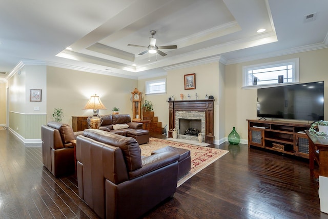 living room featuring ornamental molding, a tray ceiling, wood-type flooring, and a fireplace