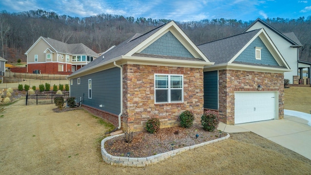 craftsman-style house with fence, a garage, stone siding, driveway, and a front lawn