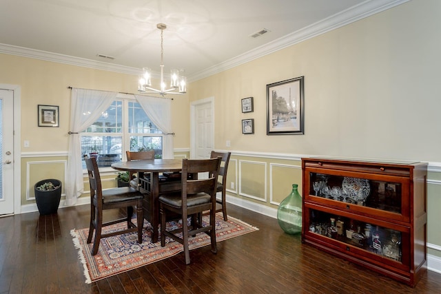 dining room featuring visible vents, a decorative wall, wood finished floors, and ornamental molding