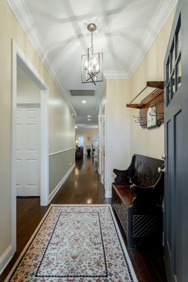 corridor with visible vents, a wainscoted wall, ornamental molding, wood finished floors, and a notable chandelier