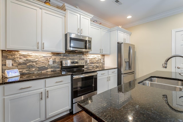 kitchen featuring visible vents, decorative backsplash, stainless steel appliances, crown molding, and a sink