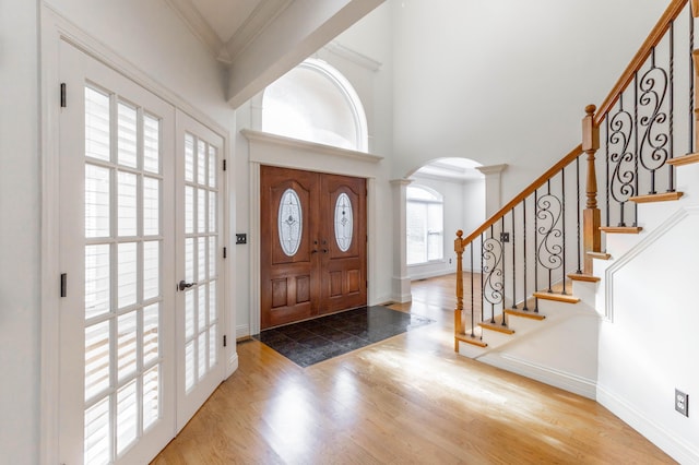 entryway with hardwood / wood-style flooring, ornamental molding, and a high ceiling