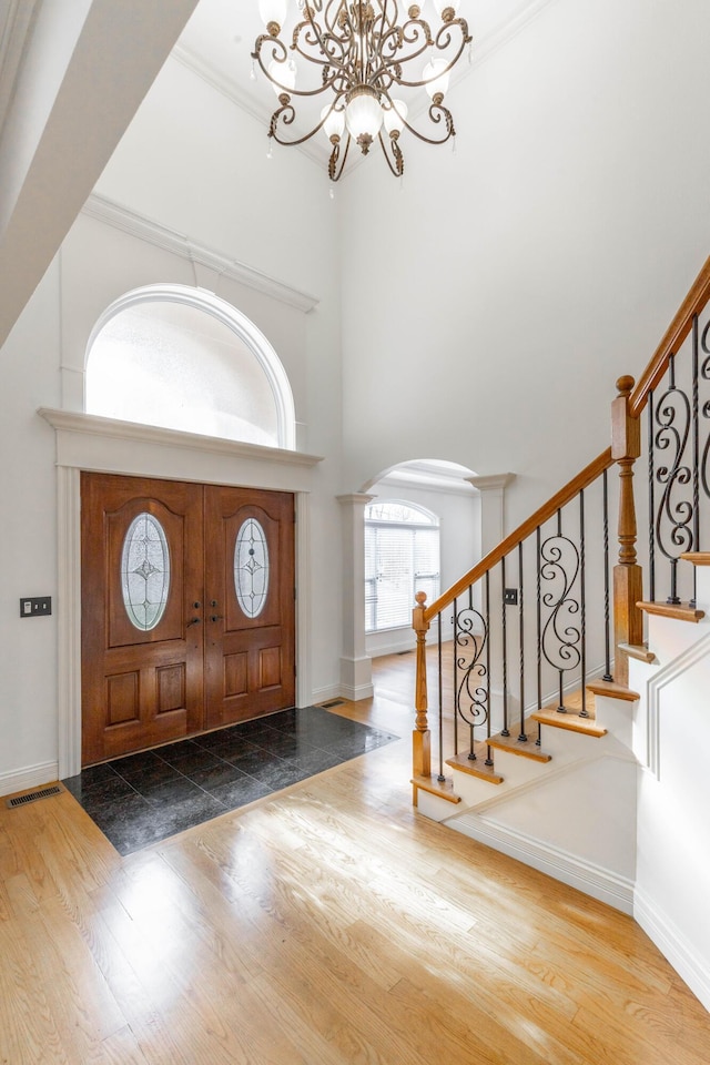 entrance foyer featuring wood-type flooring, a chandelier, and a high ceiling