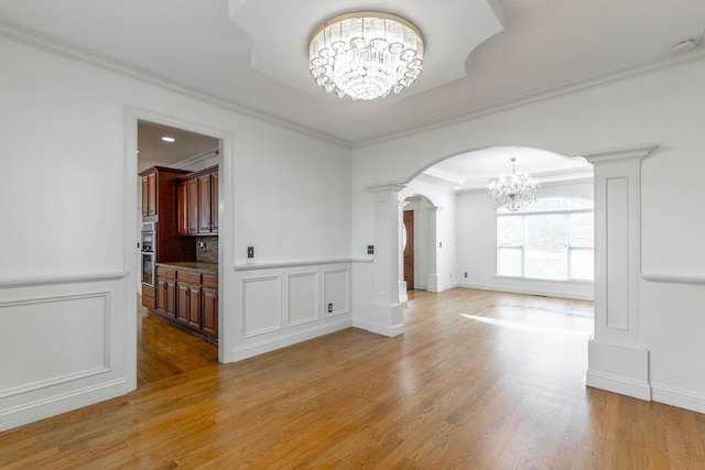 empty room featuring ornamental molding, a notable chandelier, and light hardwood / wood-style floors