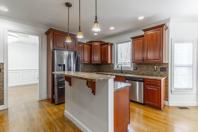 kitchen with a breakfast bar area, decorative light fixtures, dark stone countertops, appliances with stainless steel finishes, and a kitchen island