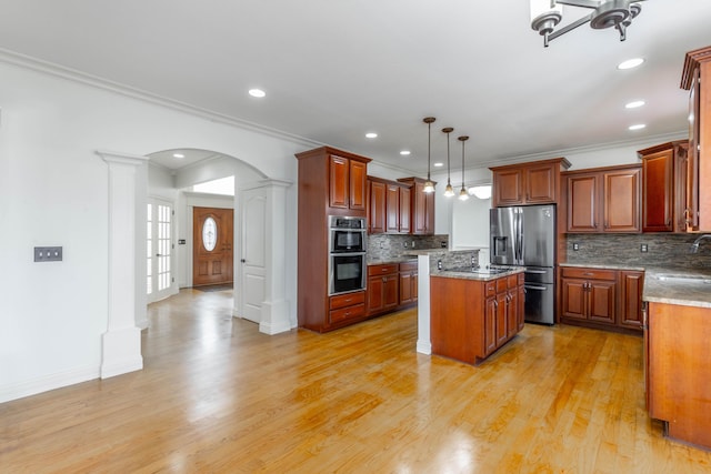 kitchen with appliances with stainless steel finishes, a center island, light stone counters, decorative light fixtures, and ornate columns