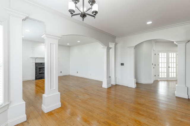 unfurnished living room with ornate columns, crown molding, a high end fireplace, and light wood-type flooring