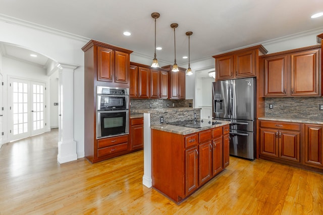 kitchen featuring ornate columns, ornamental molding, appliances with stainless steel finishes, pendant lighting, and dark stone counters