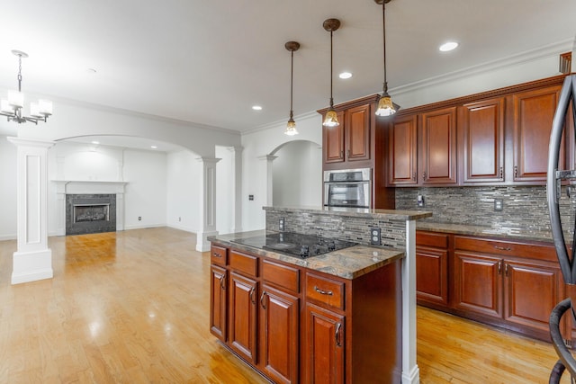 kitchen with ornate columns, pendant lighting, backsplash, black electric stovetop, and stainless steel oven