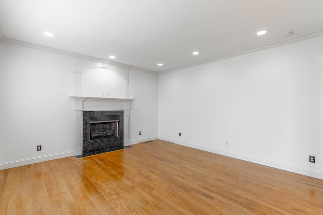 unfurnished living room with a premium fireplace, ornamental molding, and light hardwood / wood-style floors