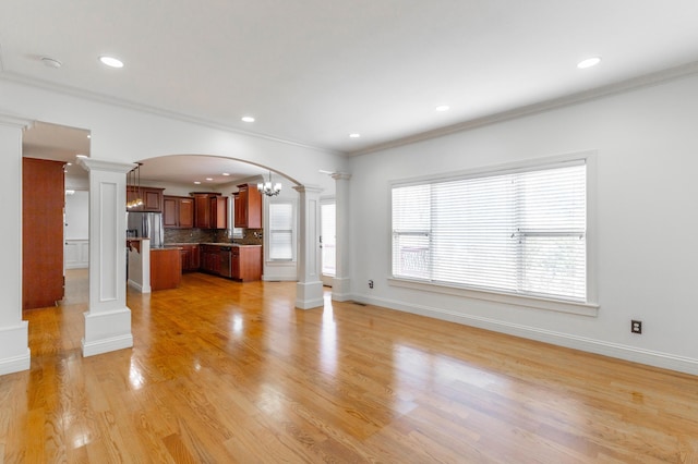 unfurnished living room featuring decorative columns, ornamental molding, a notable chandelier, and light wood-type flooring