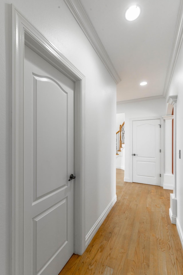 hallway with ornamental molding and light hardwood / wood-style flooring