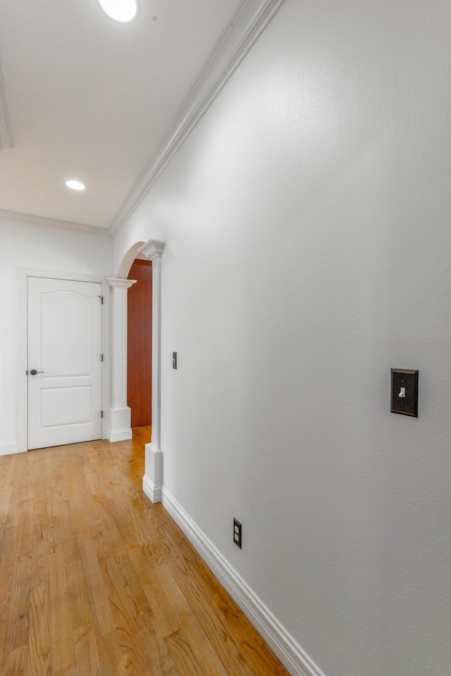 hallway featuring crown molding, decorative columns, and light hardwood / wood-style floors