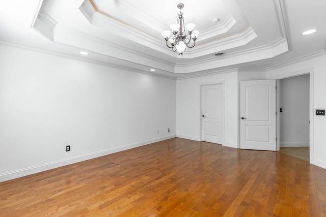 unfurnished bedroom featuring crown molding, a notable chandelier, a tray ceiling, and wood-type flooring