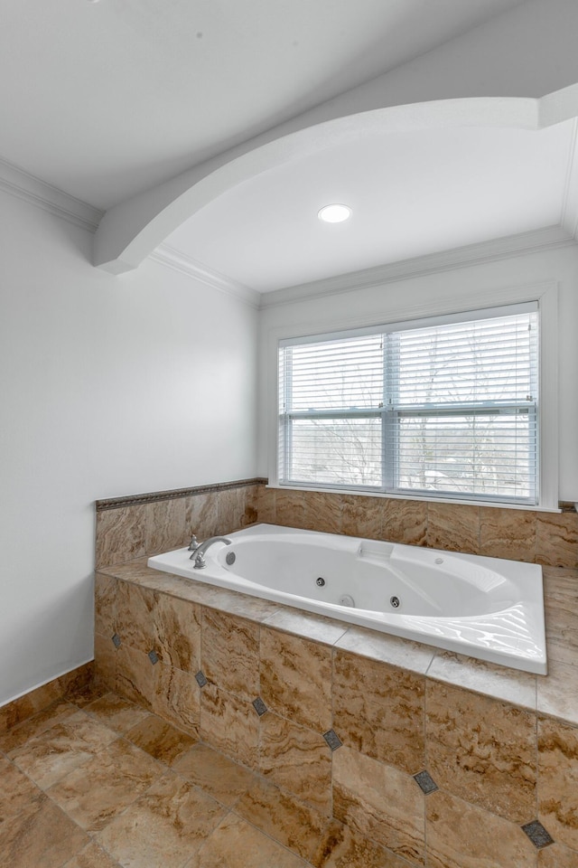 bathroom with ornamental molding and a relaxing tiled tub