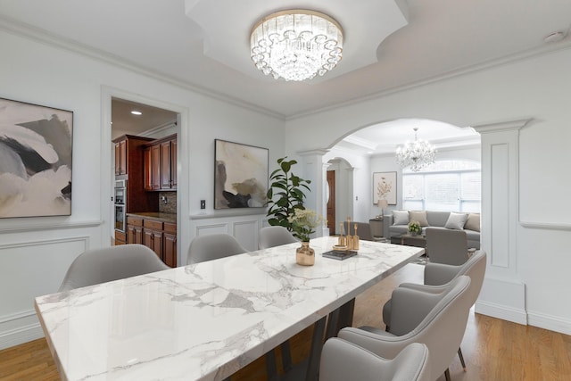 dining area featuring crown molding, a chandelier, and light hardwood / wood-style flooring