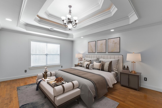 bedroom with a raised ceiling, dark hardwood / wood-style floors, and a notable chandelier