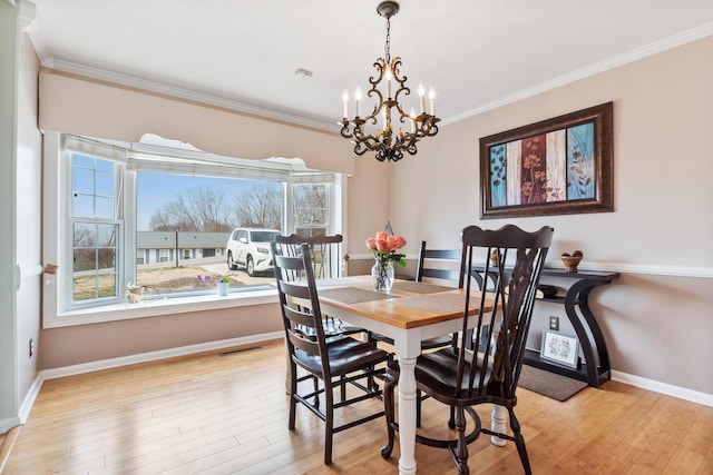 dining room featuring ornamental molding, a notable chandelier, and light hardwood / wood-style floors