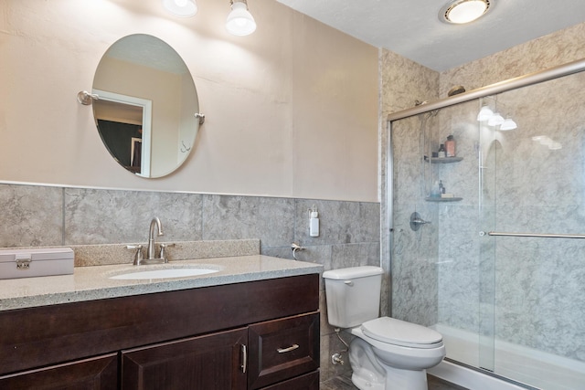 bathroom featuring tile walls, vanity, toilet, and walk in shower