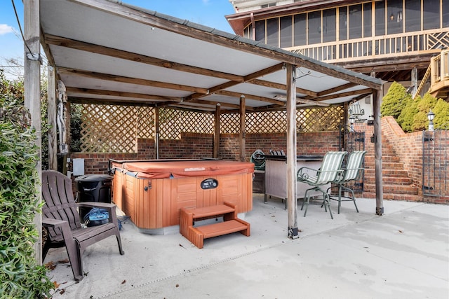 view of patio with a hot tub and a sunroom