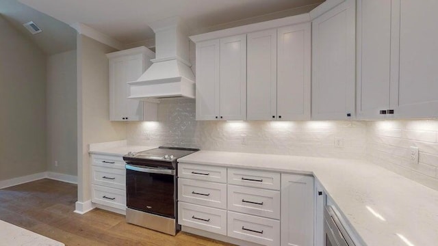 kitchen featuring premium range hood, tasteful backsplash, electric stove, light hardwood / wood-style floors, and white cabinets