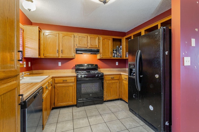 kitchen with brown cabinets, under cabinet range hood, light countertops, black appliances, and a sink