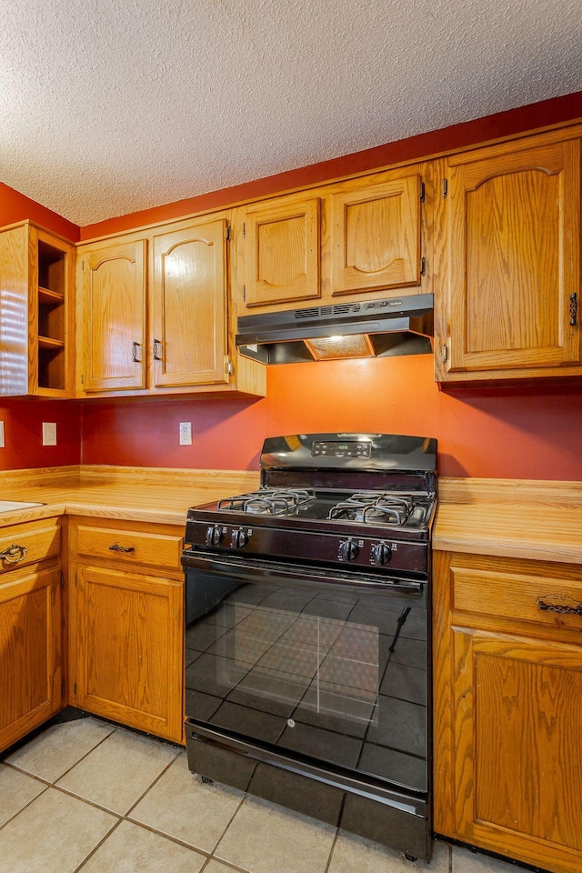 kitchen with light countertops, black range with gas stovetop, brown cabinets, and under cabinet range hood