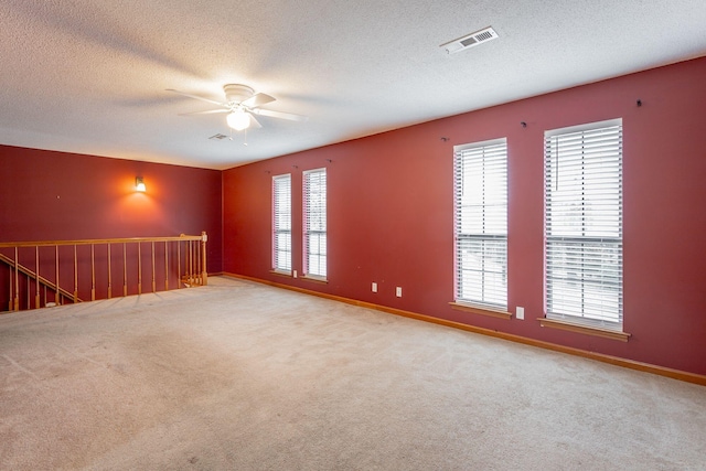 empty room featuring light carpet, visible vents, and baseboards