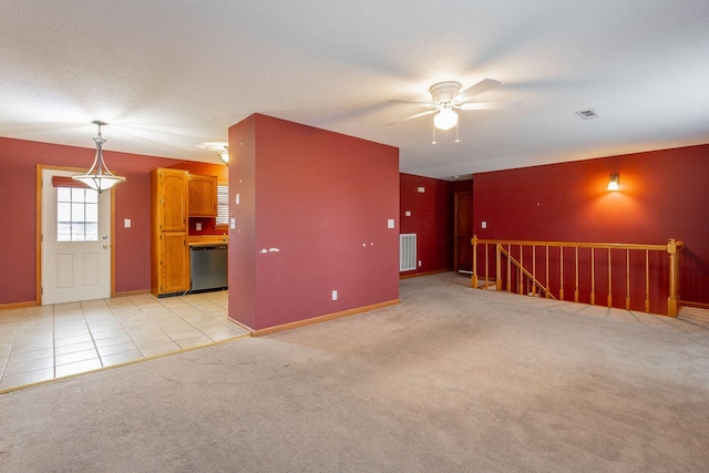 spare room featuring light tile patterned floors, visible vents, a textured ceiling, and light colored carpet