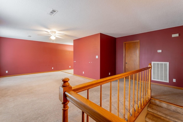 stairway featuring a textured ceiling, carpet flooring, visible vents, and baseboards