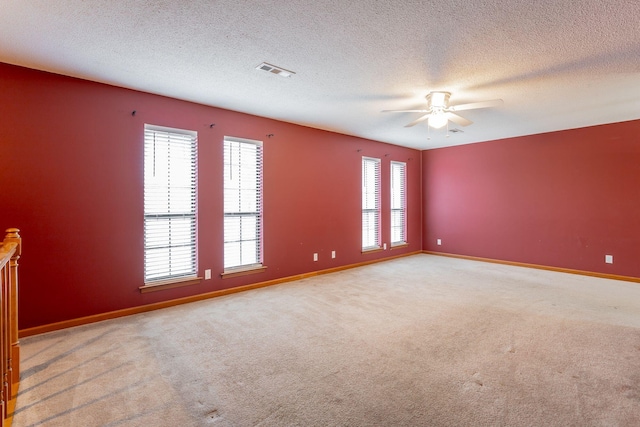 spare room featuring visible vents, light carpet, ceiling fan, a textured ceiling, and baseboards