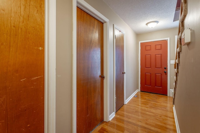 entryway featuring a textured ceiling, light wood finished floors, and baseboards