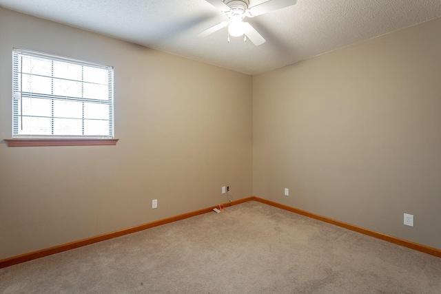 spare room featuring a ceiling fan, light carpet, a textured ceiling, and baseboards