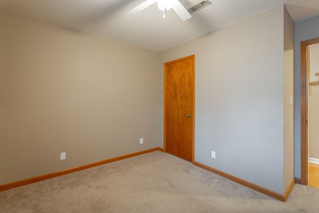 empty room featuring baseboards, visible vents, a textured ceiling, and light colored carpet