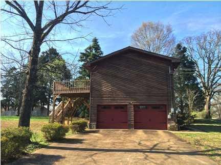 view of home's exterior featuring a deck, driveway, an attached garage, and stairs