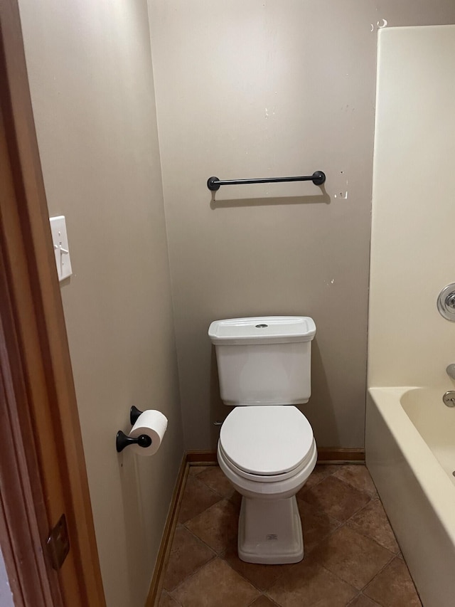 full bath featuring toilet, a tub, baseboards, and tile patterned floors