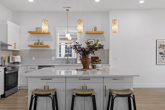 kitchen featuring electric stove, sink, pendant lighting, light stone countertops, and a kitchen bar