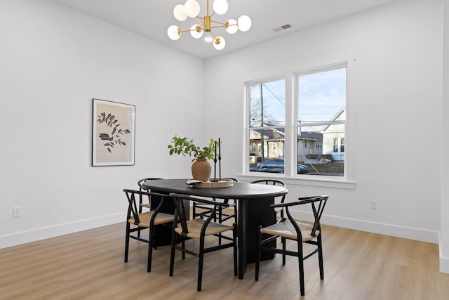 dining space with an inviting chandelier and light hardwood / wood-style floors