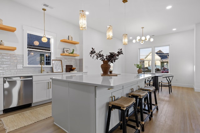 kitchen featuring pendant lighting, a breakfast bar, dishwasher, white cabinetry, and a center island