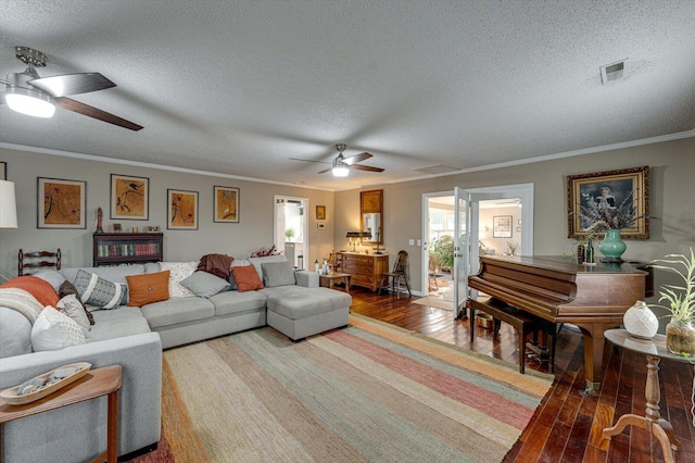 living room with wood-type flooring, ornamental molding, ceiling fan, and a textured ceiling