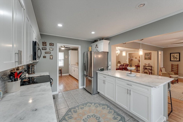 kitchen with light stone counters, stainless steel appliances, hanging light fixtures, and white cabinets