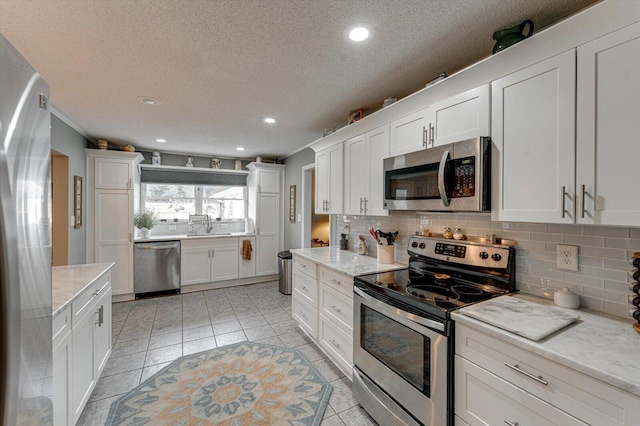 kitchen featuring light stone counters, white cabinetry, tasteful backsplash, light tile patterned floors, and stainless steel appliances