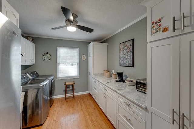 laundry area with crown molding, cabinets, separate washer and dryer, a textured ceiling, and light hardwood / wood-style floors