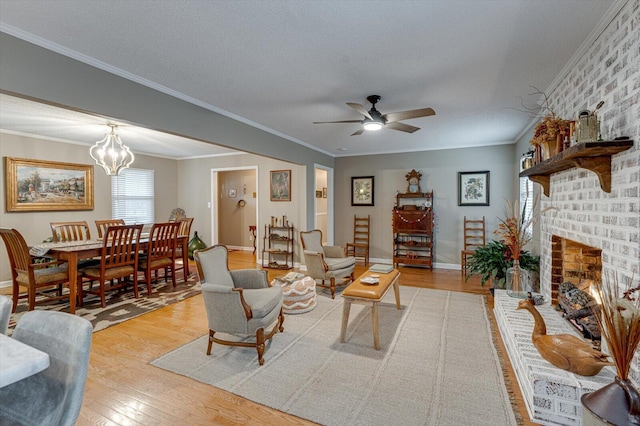 living room featuring crown molding, a fireplace, light hardwood / wood-style floors, a textured ceiling, and ceiling fan with notable chandelier