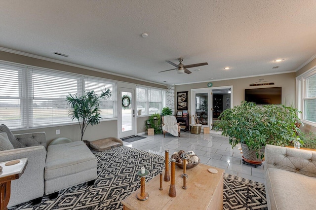 living room with ceiling fan, ornamental molding, a textured ceiling, and light tile patterned floors